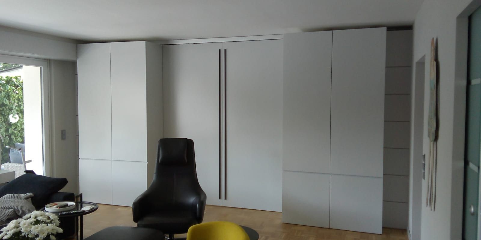 Ein Wohnzimmer mit weißen Schränken und einem schwarzen Stuhl