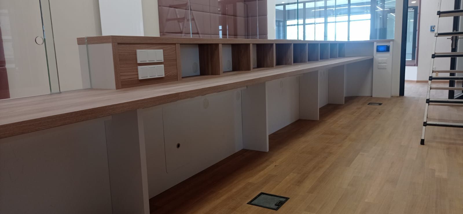 Eine lange Reihe von Holzschreibtischen in einem Raum mit Holzboden.
