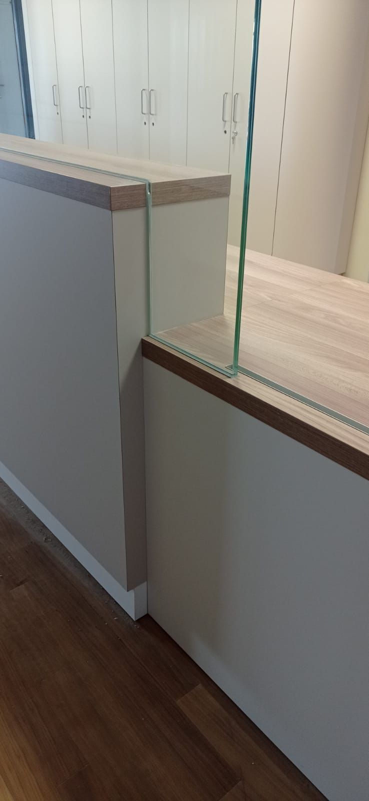 Eine Theke mit einer Holzplatte und einem Glasregal in einem Raum.