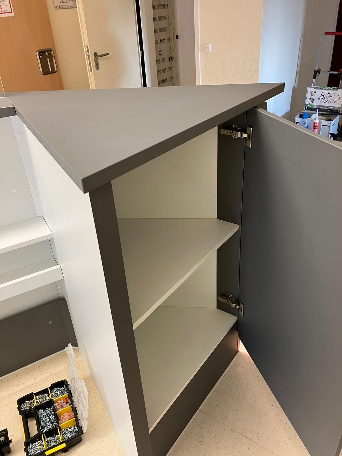 Ein Schrank mit offener Tür und Regalen darin.