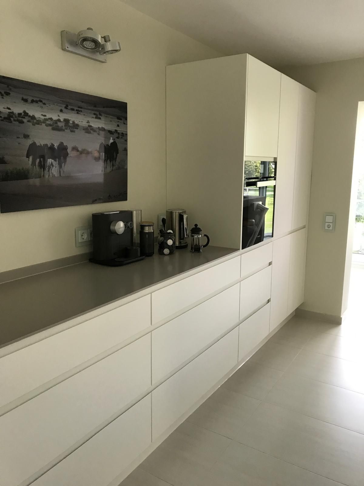 Eine Küche mit weißen Schränken und einem Bild an der Wand