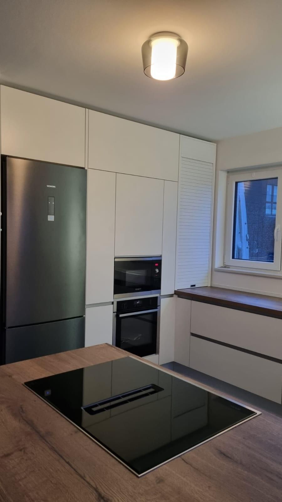 Eine Küche mit Herd, Backofen, Kühlschrank und Mikrowelle.