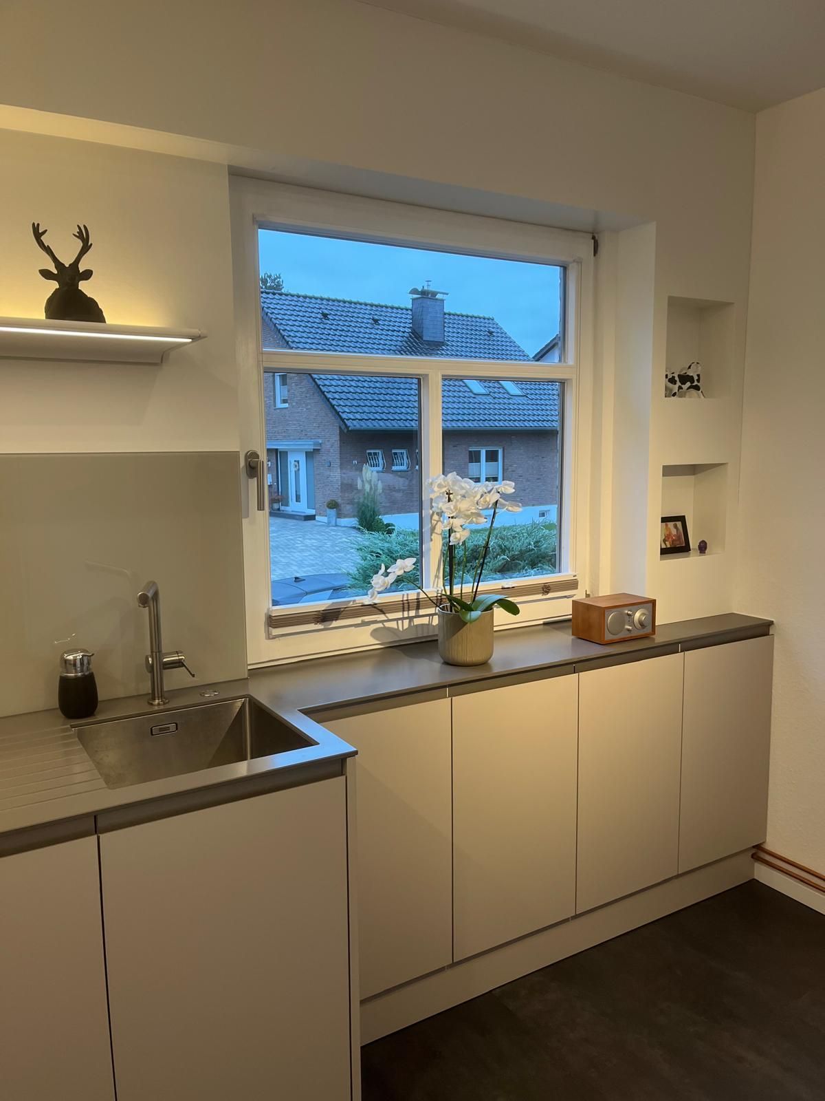 Eine Küche mit Spüle und einem Fenster mit Blick auf ein Haus.