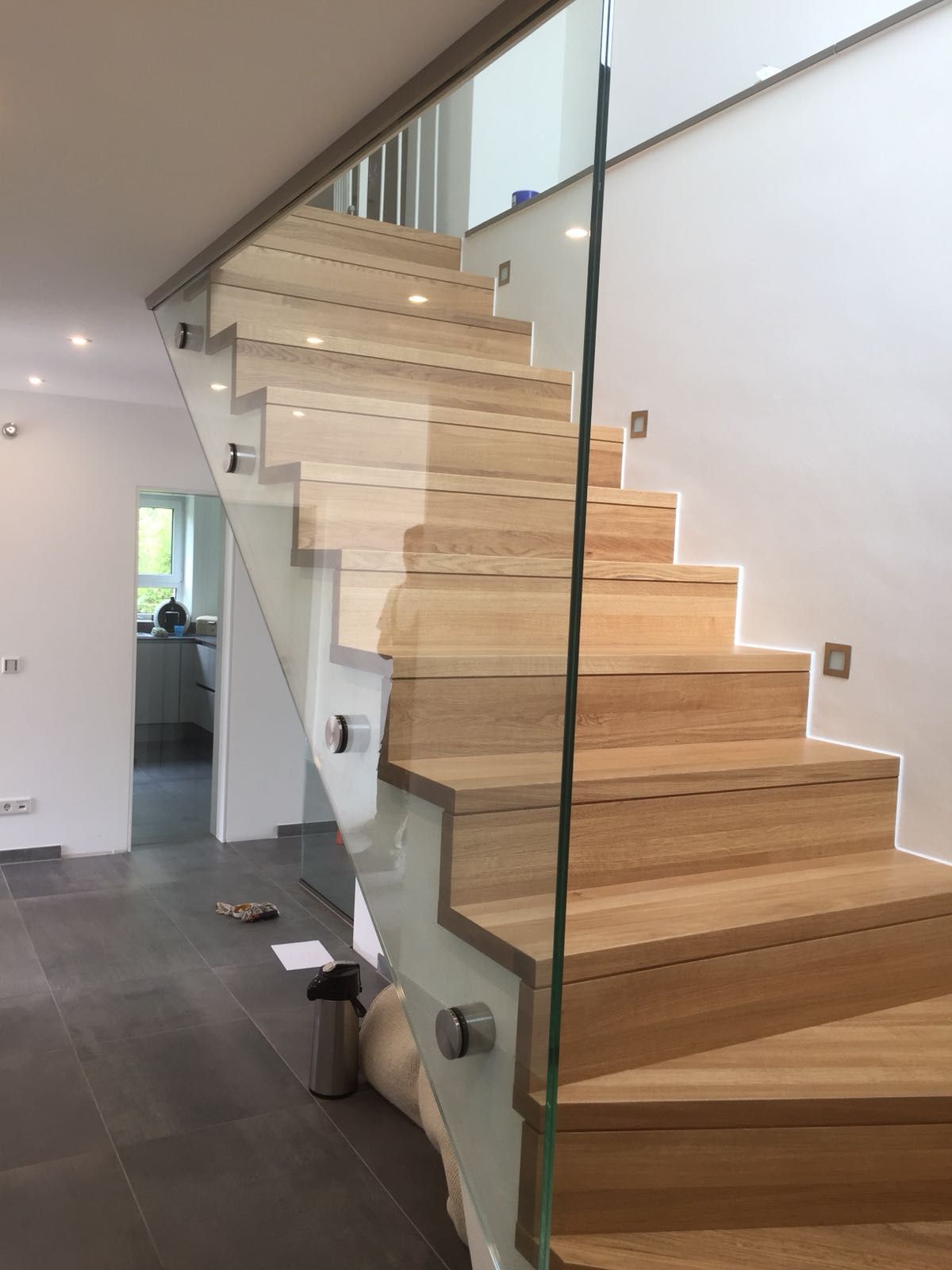 Eine Holztreppe mit einem Glasgeländer in einem Haus.