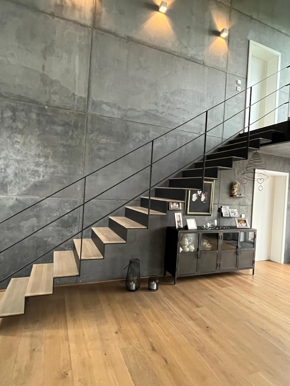 Eine Treppe in einem Wohnzimmer mit Holzboden und einer Betonwand.