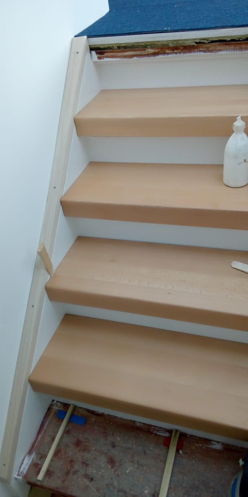 Eine Holztreppe mit einer Flasche Klebstoff auf den Stufen.