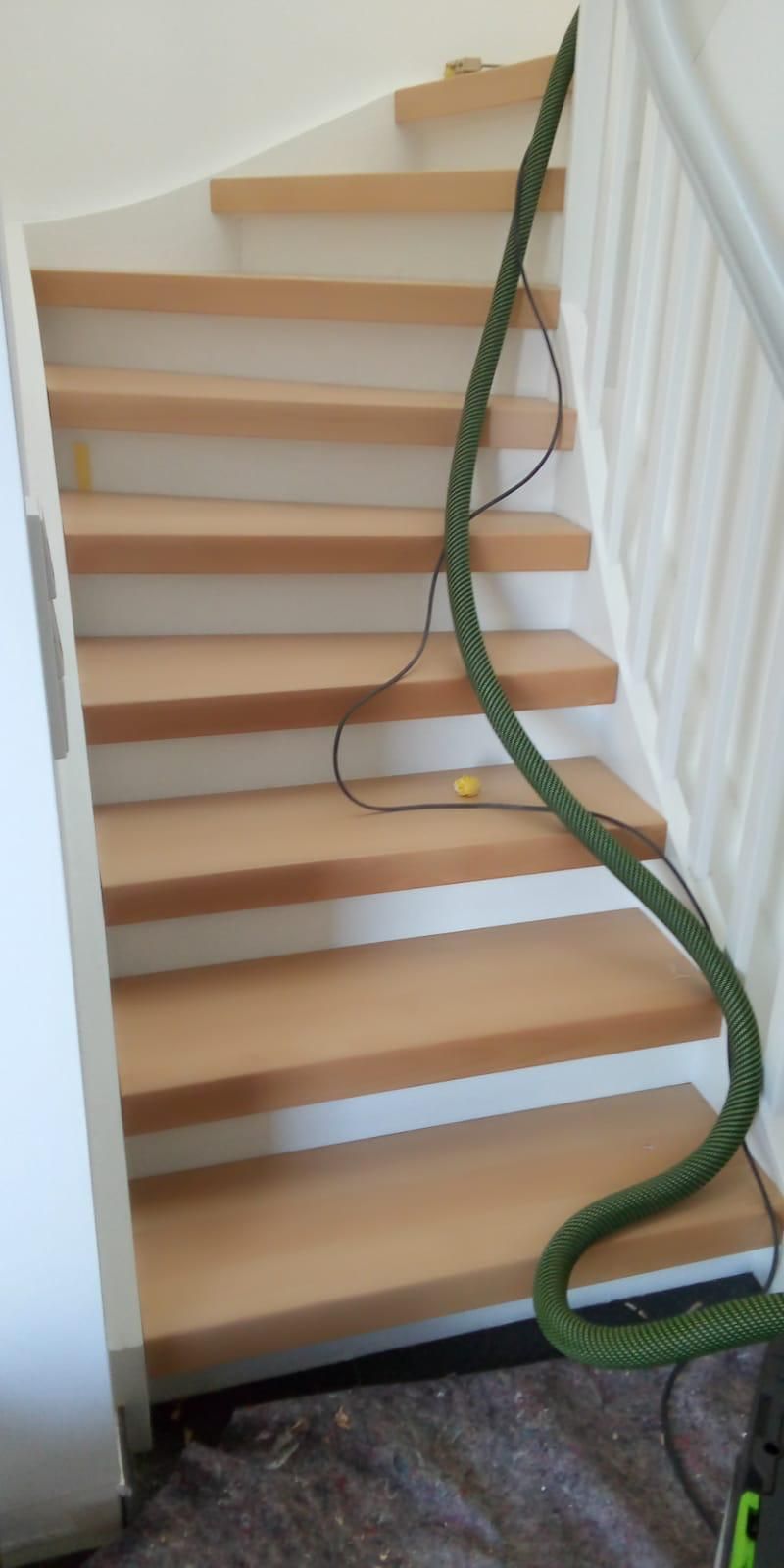 Auf einer Holztreppe steht ein Staubsauger.