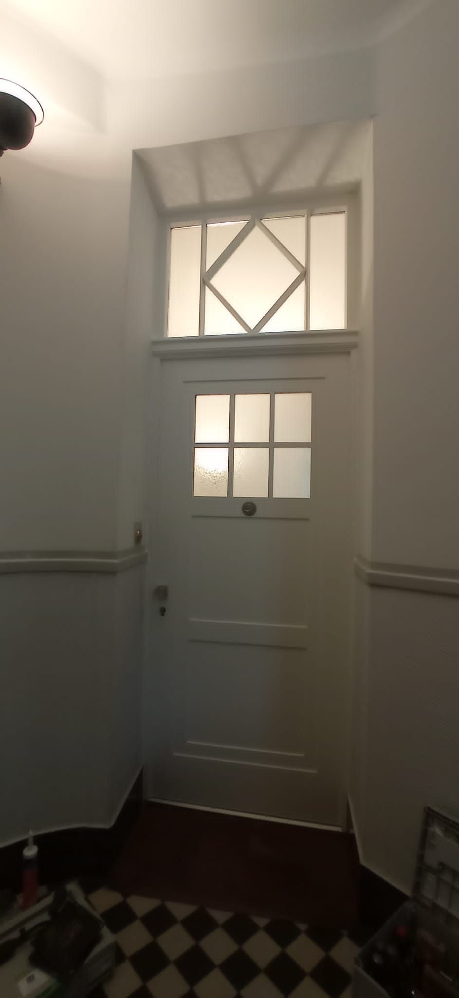 Ein Flur mit einer weißen Tür und einem karierten Boden.