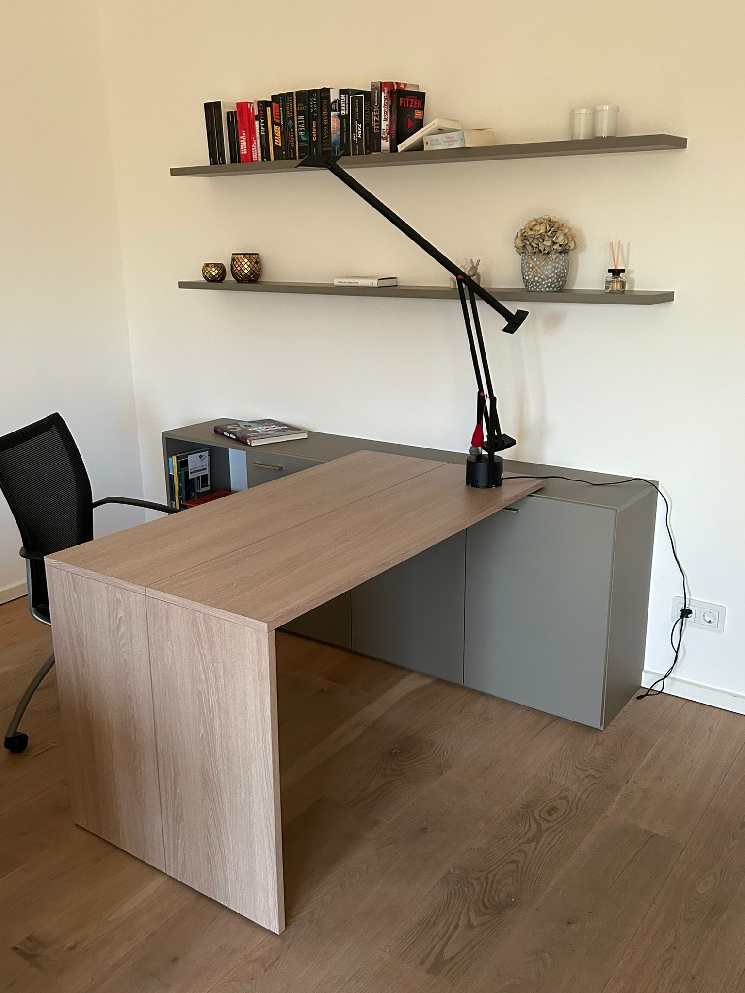Ein Schreibtisch mit einer Lampe und einem Stuhl in einem Zimmer