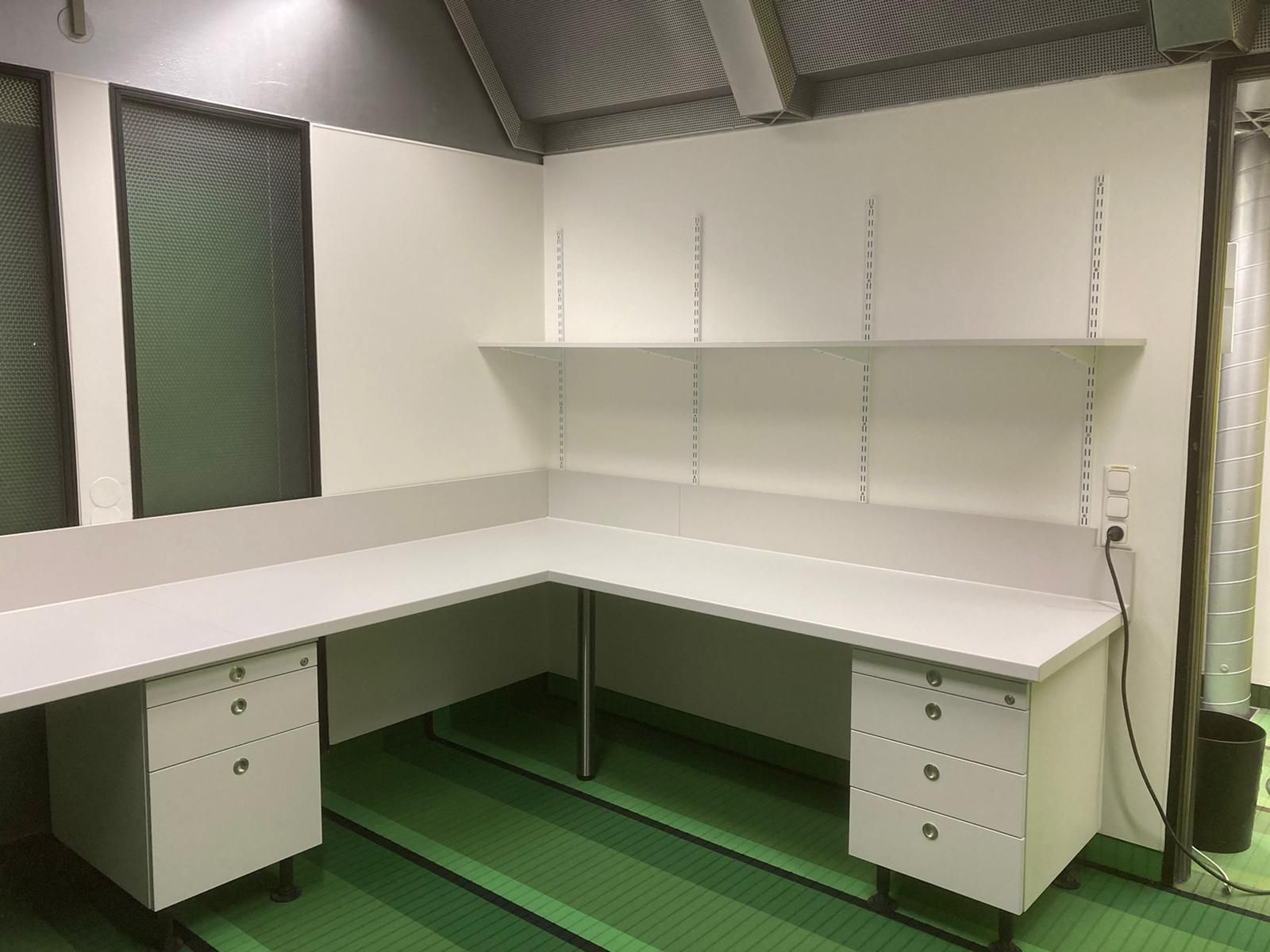 Ein weißer Schreibtisch mit Schubladen und Regalen in einem Zimmer.