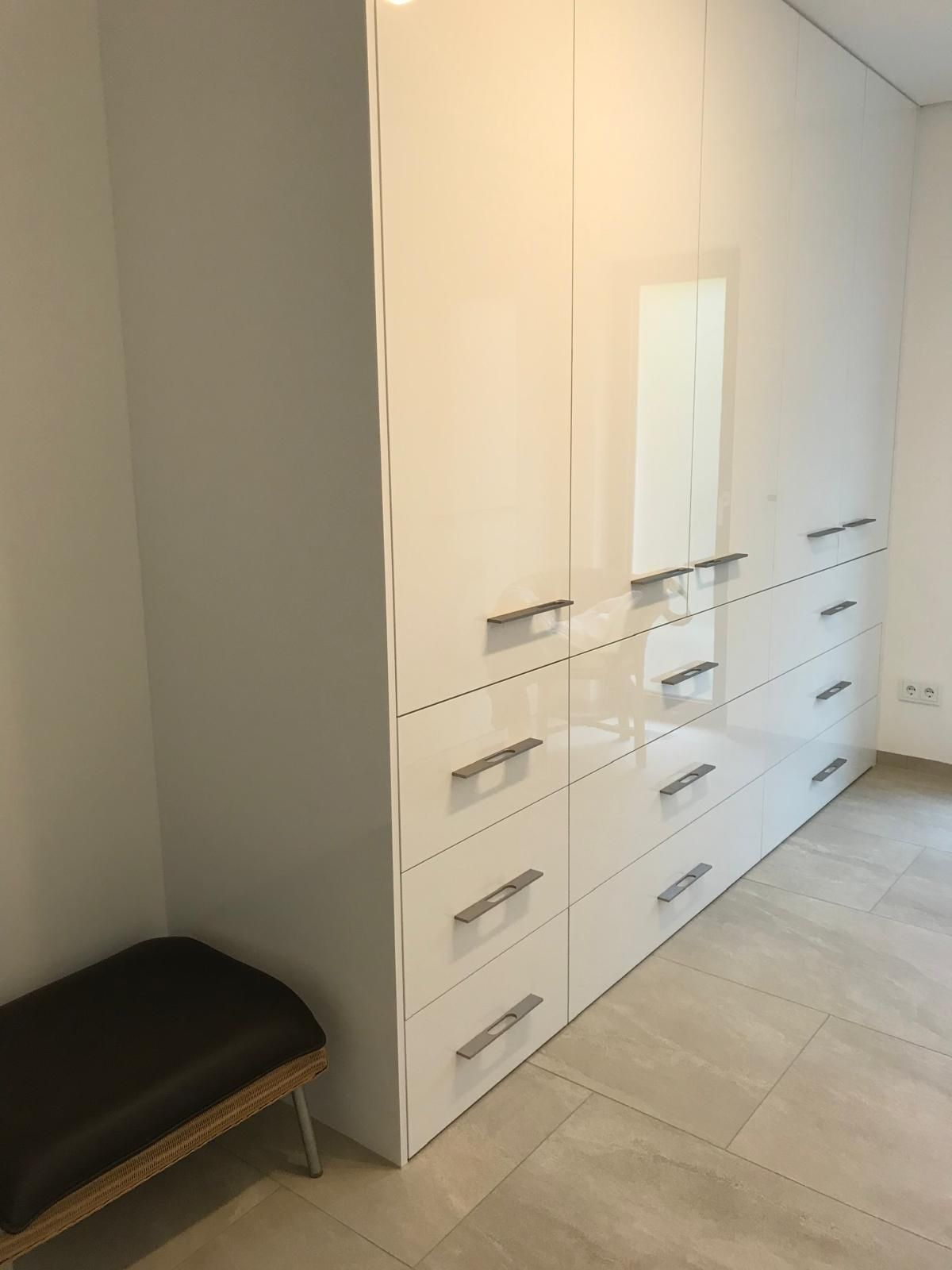Ein Raum mit weißen Schränken und Schubladen und einer Bank.