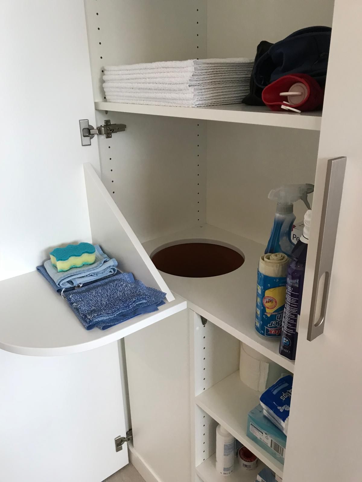 Ein weißer Schrank mit einem Mülleimer in der Ecke
