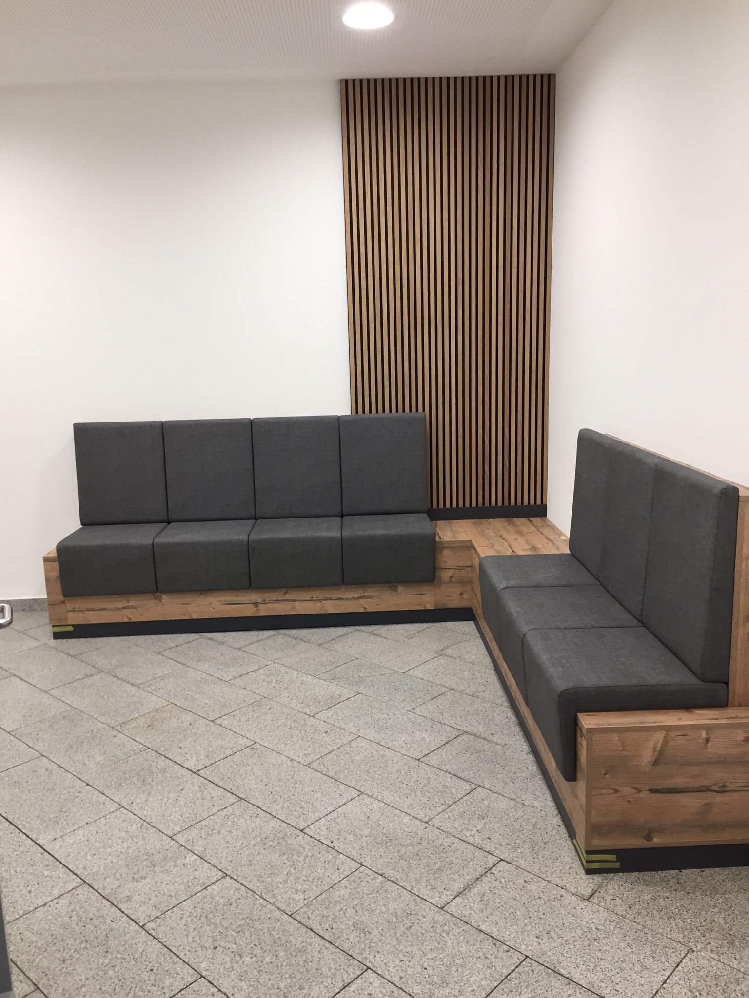 Ein Wartezimmer mit zwei Sofas und einer Holzwand.
