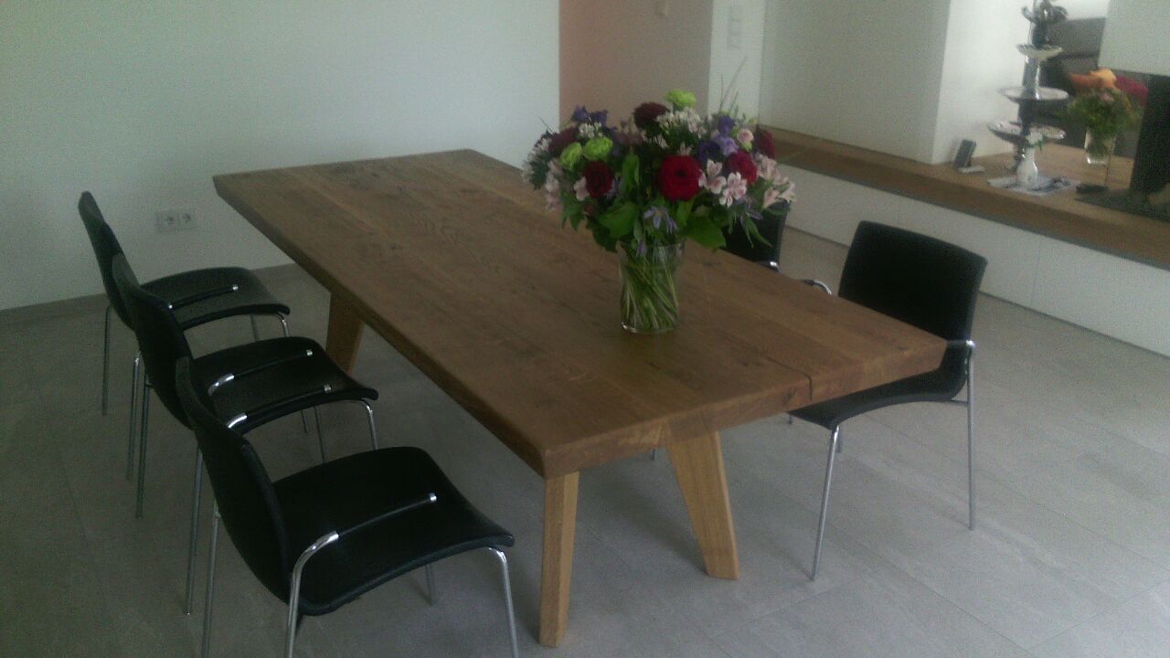 Ein Holztisch mit einer Blumenvase darauf in einem Raum mit Stühlen.