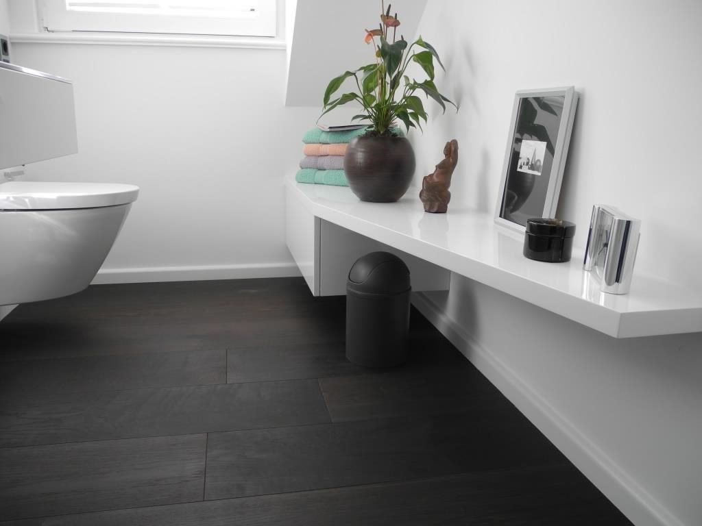 Ein Badezimmer mit einer weißen Toilette und einem schwarzen Mülleimer