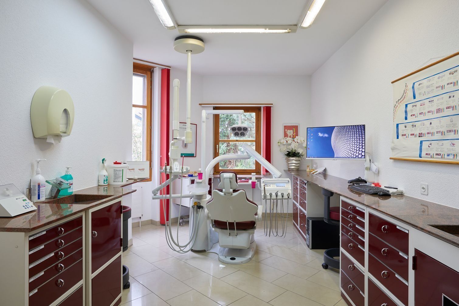 Inneneinrichtung einer Zahnarztpraxis mit Patientenstuhl, Schränken und zahnärztlicher Ausrüstung.