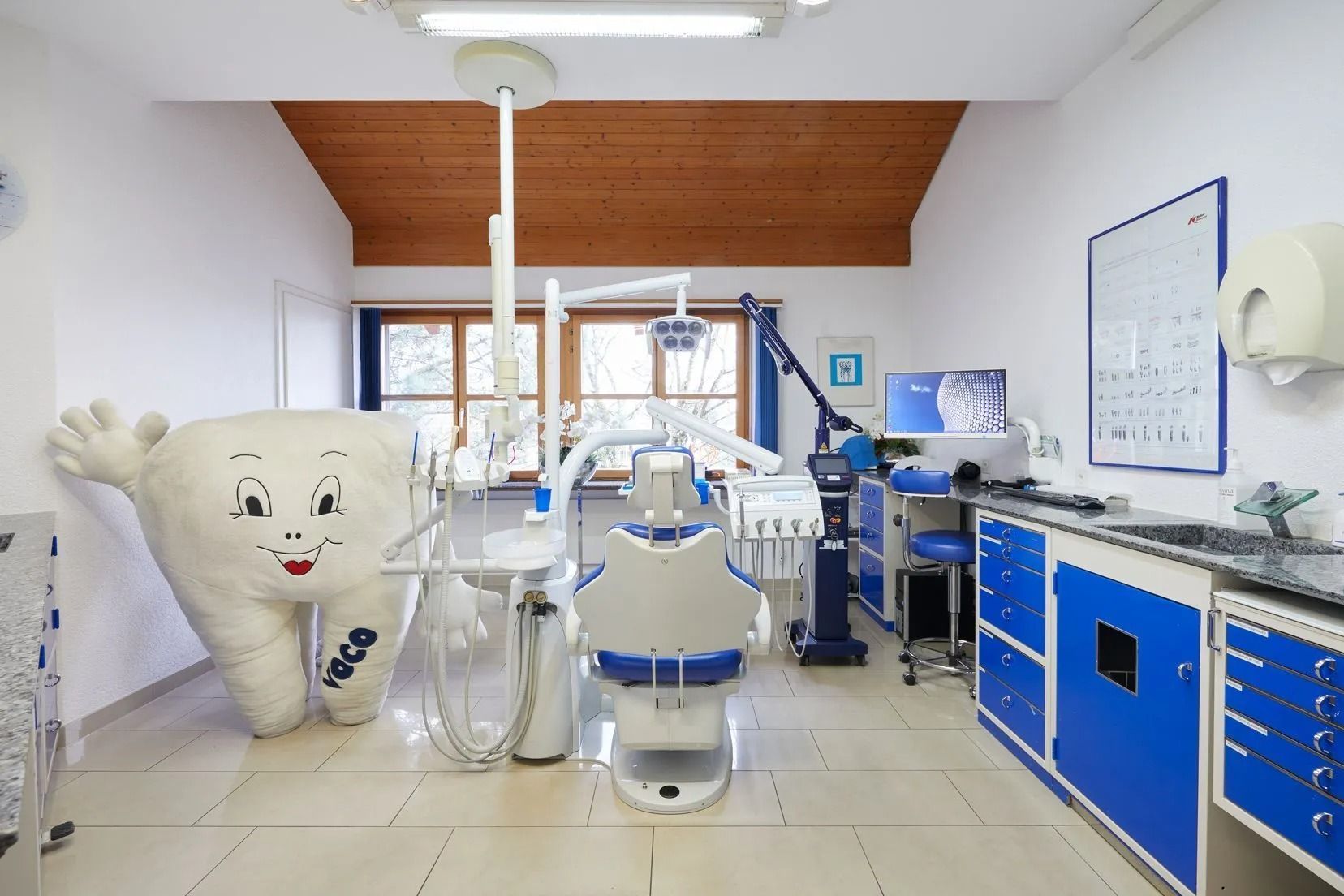 Zahnarztpraxis mit einem riesigen lächelnden Zahnmaskottchen, Stuhl und Ausrüstung.