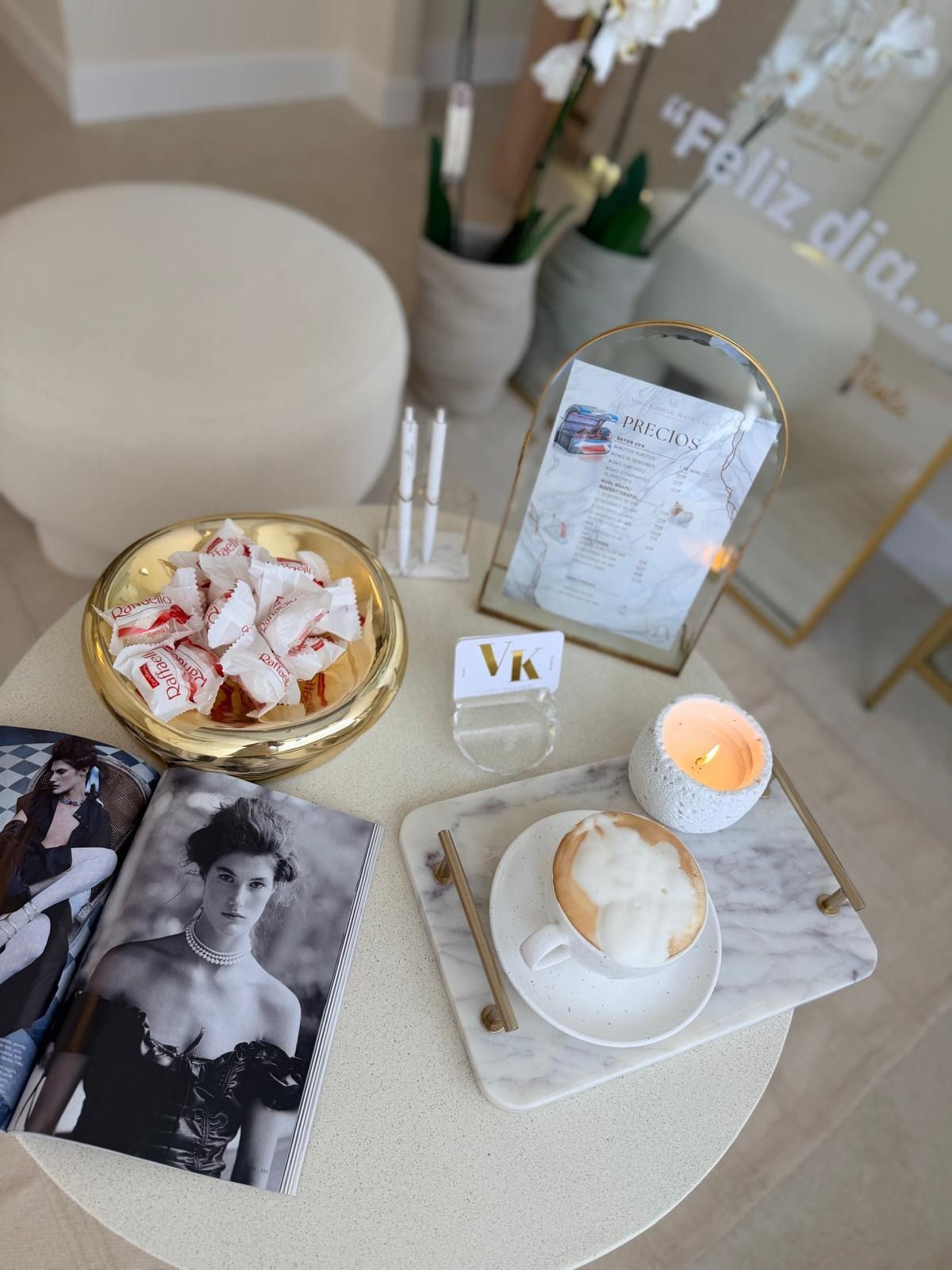 Vista desde un ángulo elevado de una mesa circular con una revista, un cuenco dorado con dulces y una taza de café