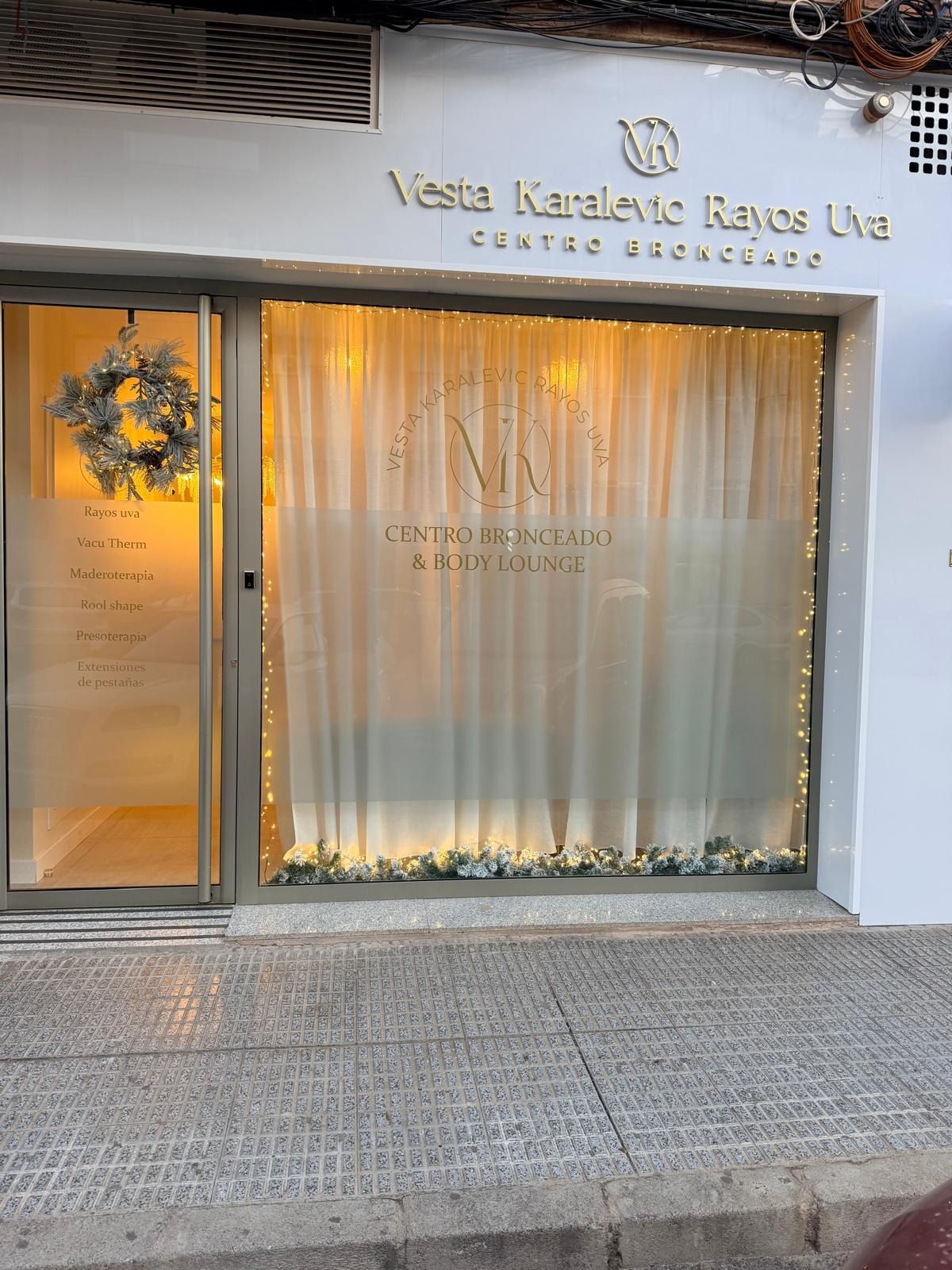 Fachada de Vesta Karalevic Rayas Uva, un centro de cuidado de la piel con un escaparate iluminado con cortinas