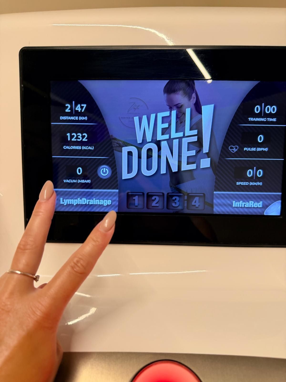 Una mano haciendo el signo de la paz frente a la pantalla de una máquina de ejercicios que muestra 