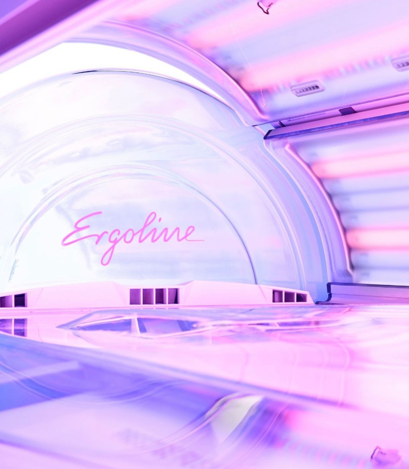 El interior de una cabina de bronceado Ergoline con luces UV rosas y moradas que brillan en toda la unidad.