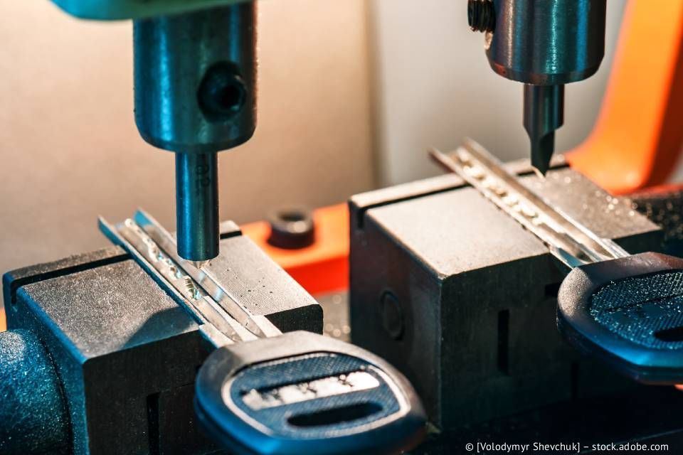 Schlüsselkopiermaschine mit zwei eingespannten Schlüsseln, die mit Schneidwerkzeugen geformt werden.