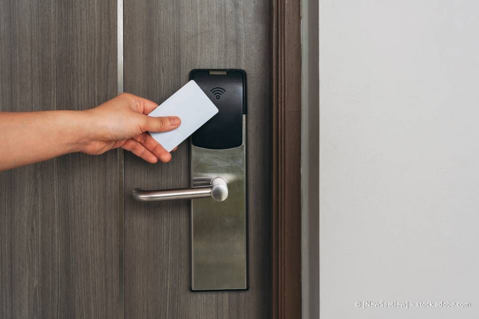 Hand, die eine Schlüsselkarte verwendet, um die Tür eines Hotelzimmers aufzuschließen.