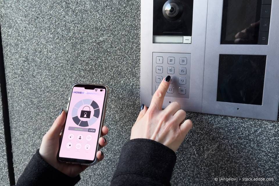 Eine Person verwendet ein Smartphone und eine Tastatur, um eine Gebäudetür aufzuschließen.