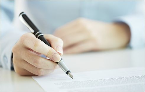 Una persona está escribiendo en un trozo de papel con una pluma fuente.