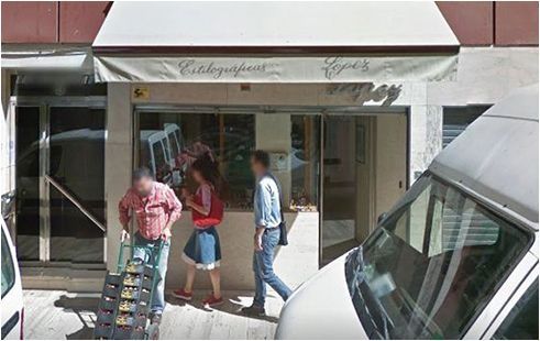 Un grupo de personas paradas afuera de una tienda con una camioneta blanca estacionada frente a ella.