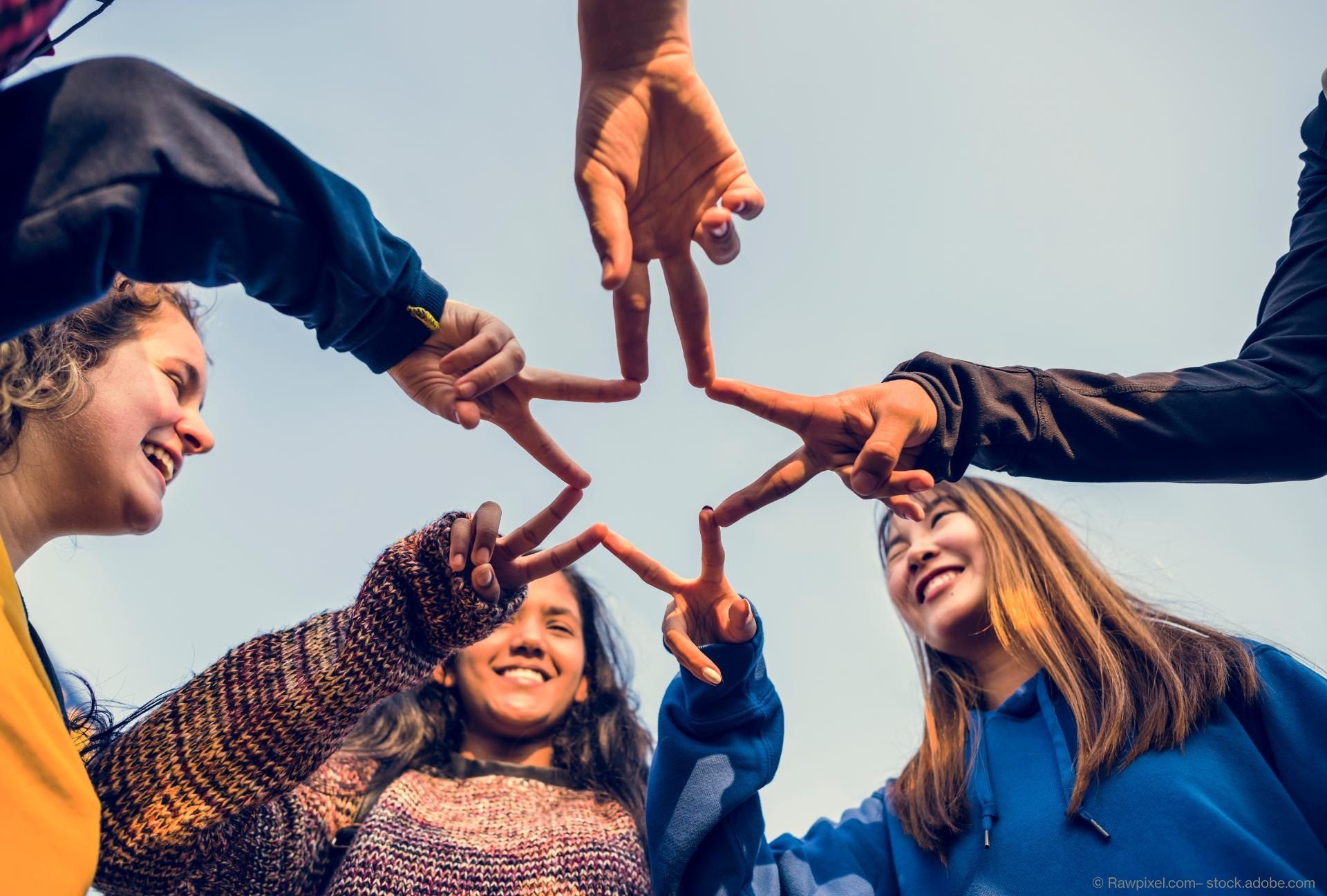 Jugendliche formen mit ihren Zeigefingern gemeinsam einen Stern