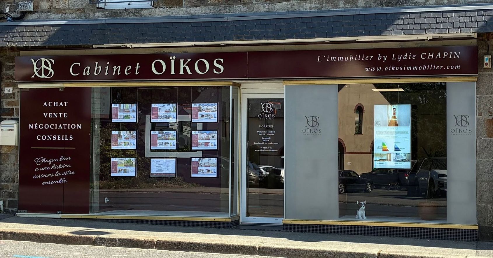 Façade du magasin « Cabinet OÏKOS » avec auvent rouge foncé, vitrines et entrée vitrée sur une rue de la ville.