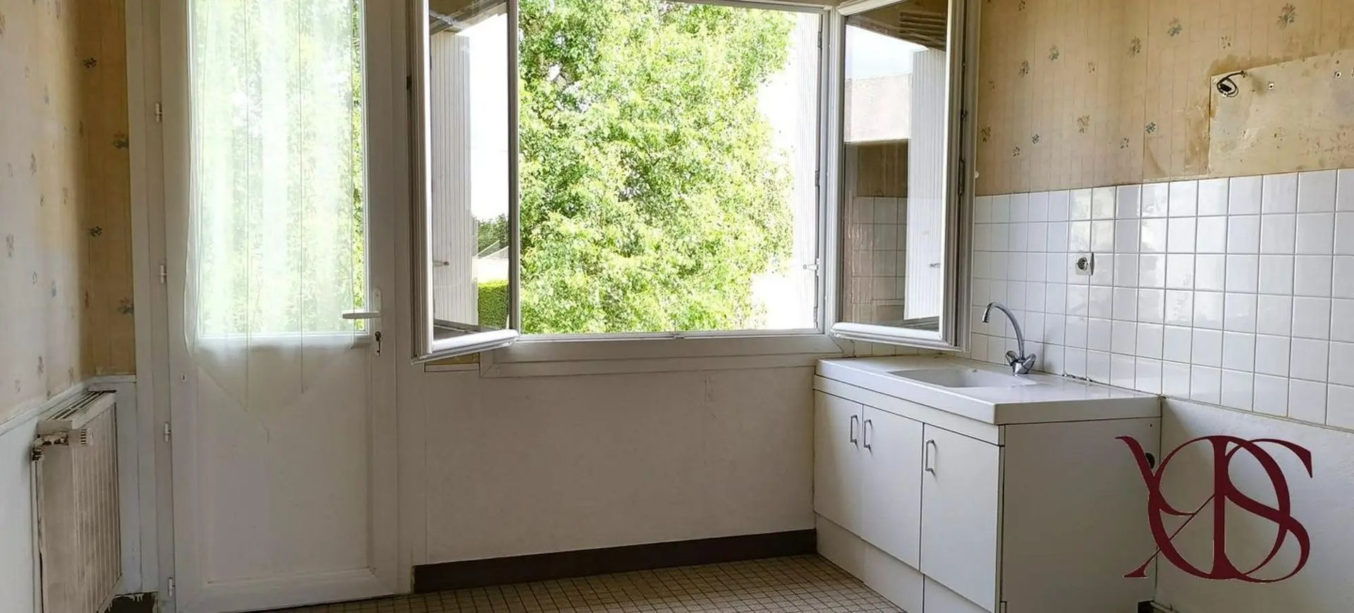 Intérieur de cuisine vide avec placards blancs et grande fenêtre.