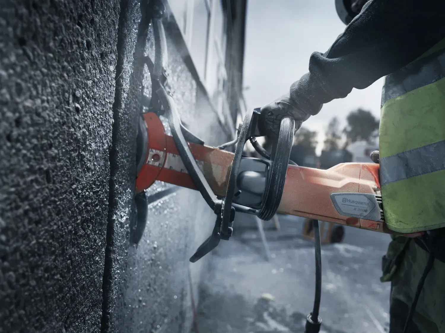 Des ouvriers utilisent une scie à béton pour découper du bitume humide sur un chantier de construction.