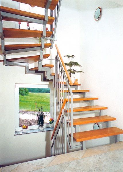 Holztreppe mit Metallstützen; Fenster mit Blick auf ein grünes Feld.