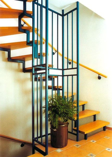 Treppe mit Holzstufen und blauem Metallgeländer, auf dem Treppenabsatz steht eine Topfpflanze.