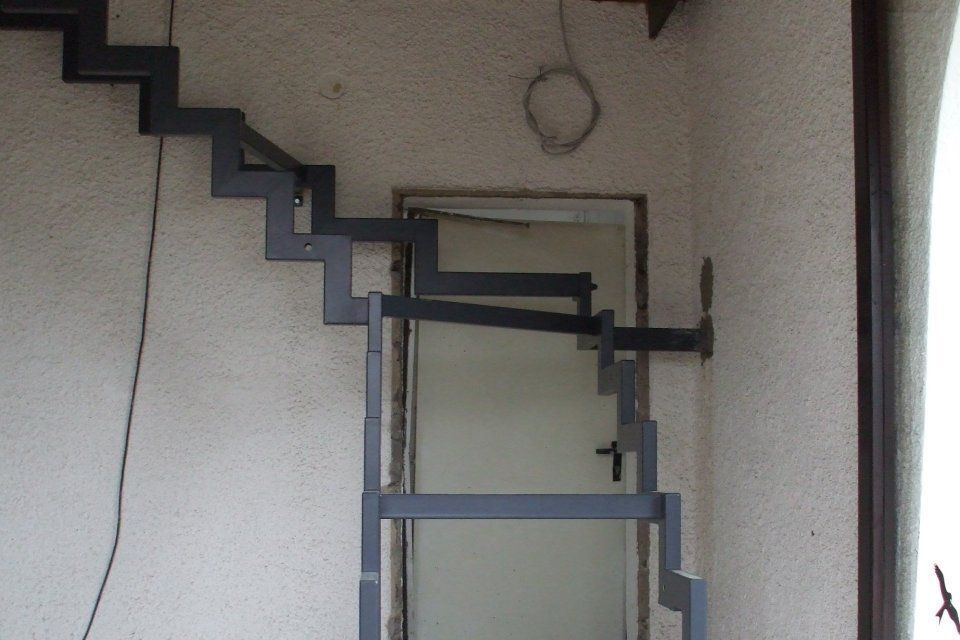 Metalltreppe, die an der Außenwand eines Gebäudes neben einem Türrahmen angebracht ist.