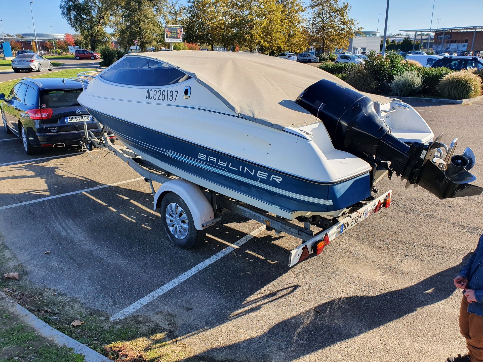 Un bateau à moteur sur une remorque, dans un parking.