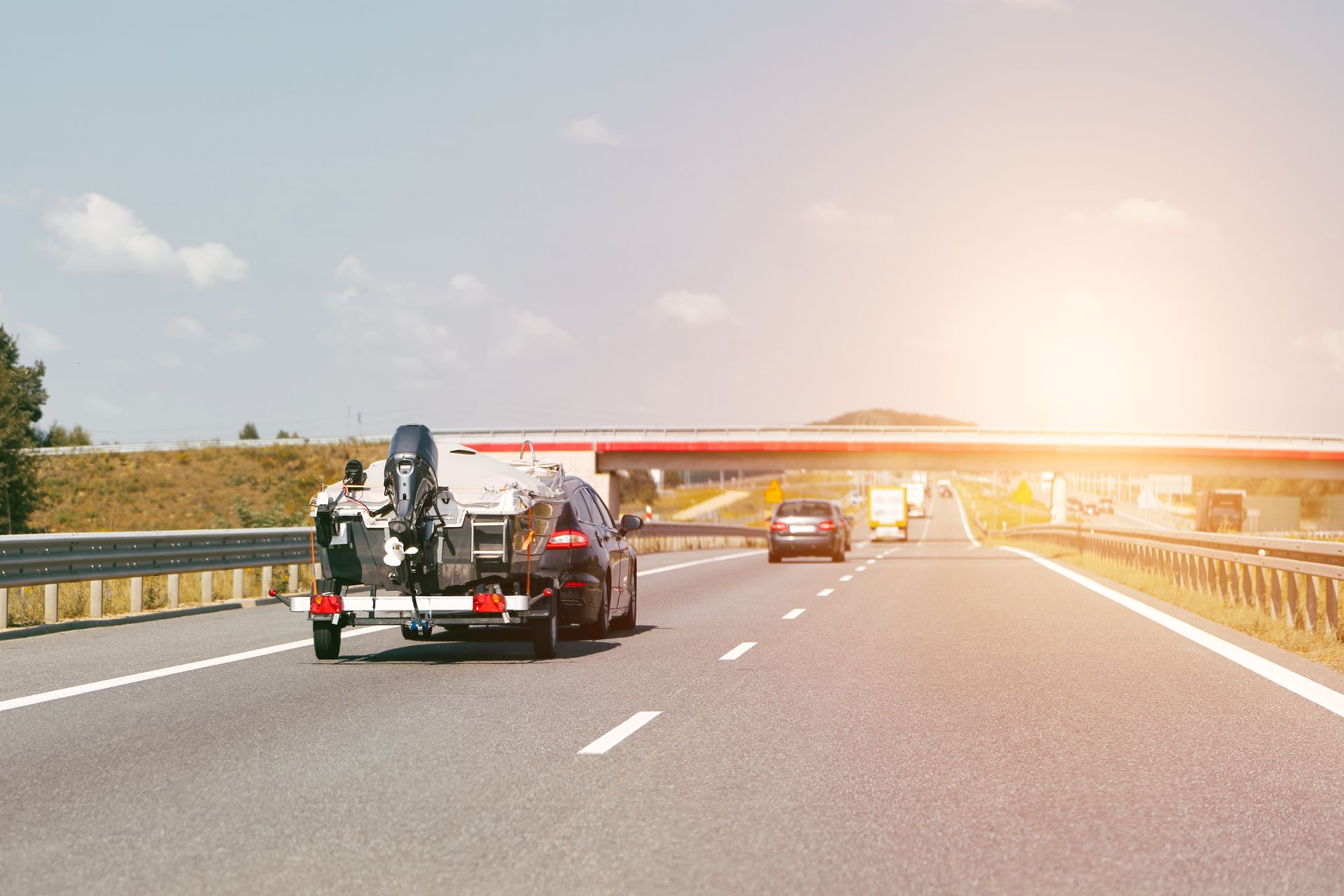 Une dépanneuse sur une autoroute transportant un bateau au coucher du soleil.