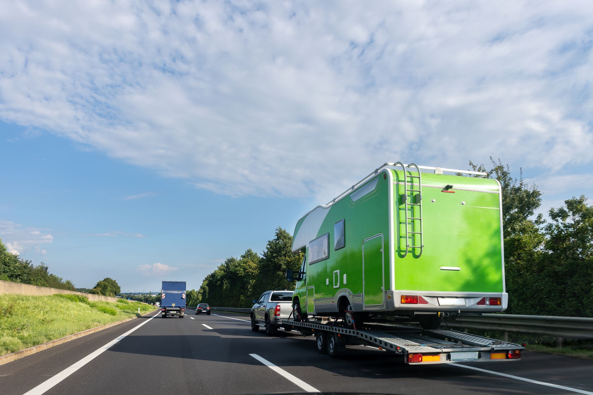 Un camping-car vert transporté sur remorque.