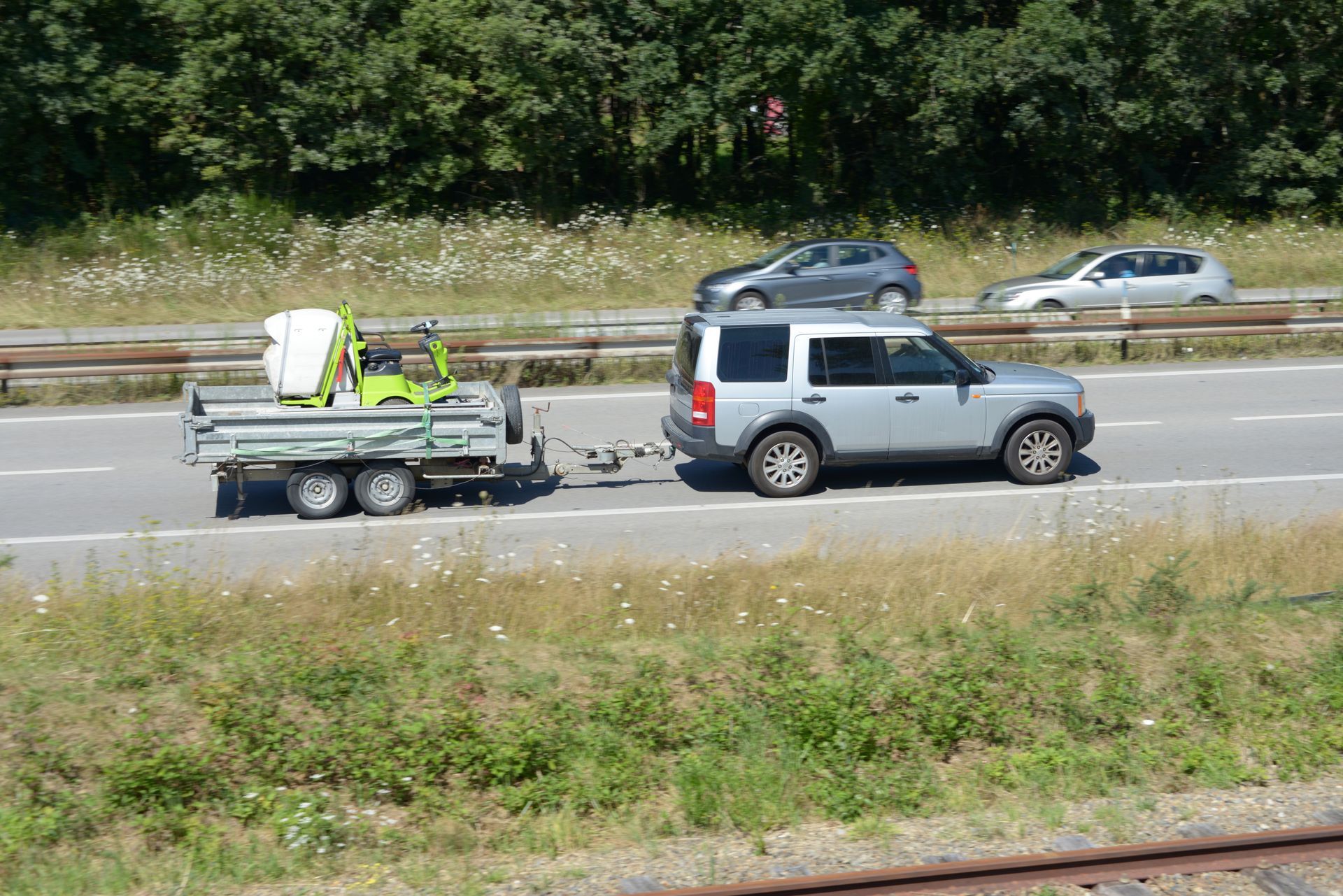 Un tracteur tondeuse est remorqué sur une route.