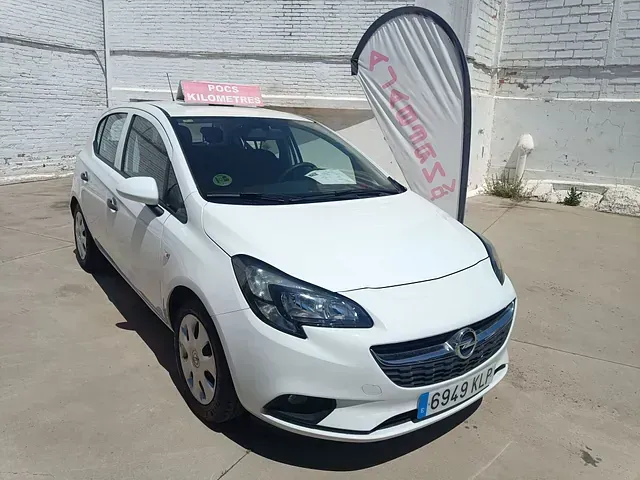 Un coche Opel blanco está aparcado delante de un edificio de ladrillo.