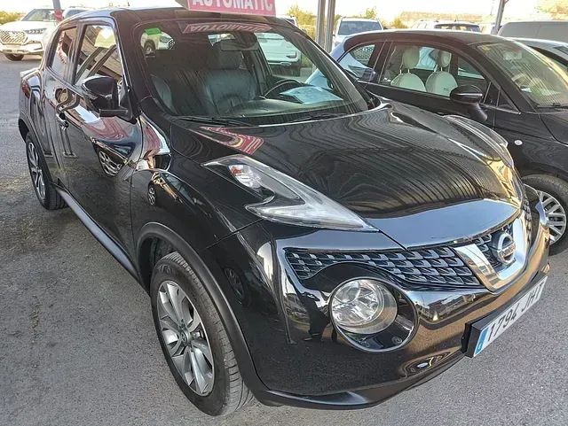 Un Nissan Juke negro está estacionado en un estacionamiento.