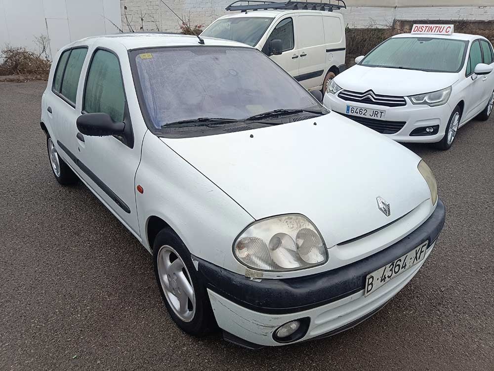 Renault Clio blanco aparcado al aire libre con otros dos vehículos al fondo.