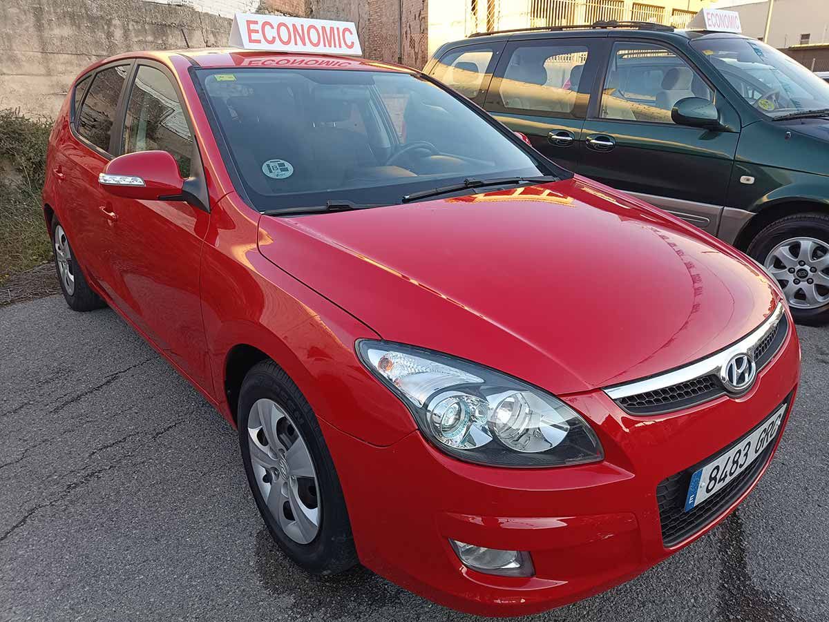 Un Hyundai i30 rojo aparcado afuera, con un letrero que dice "ECONÓMICO".