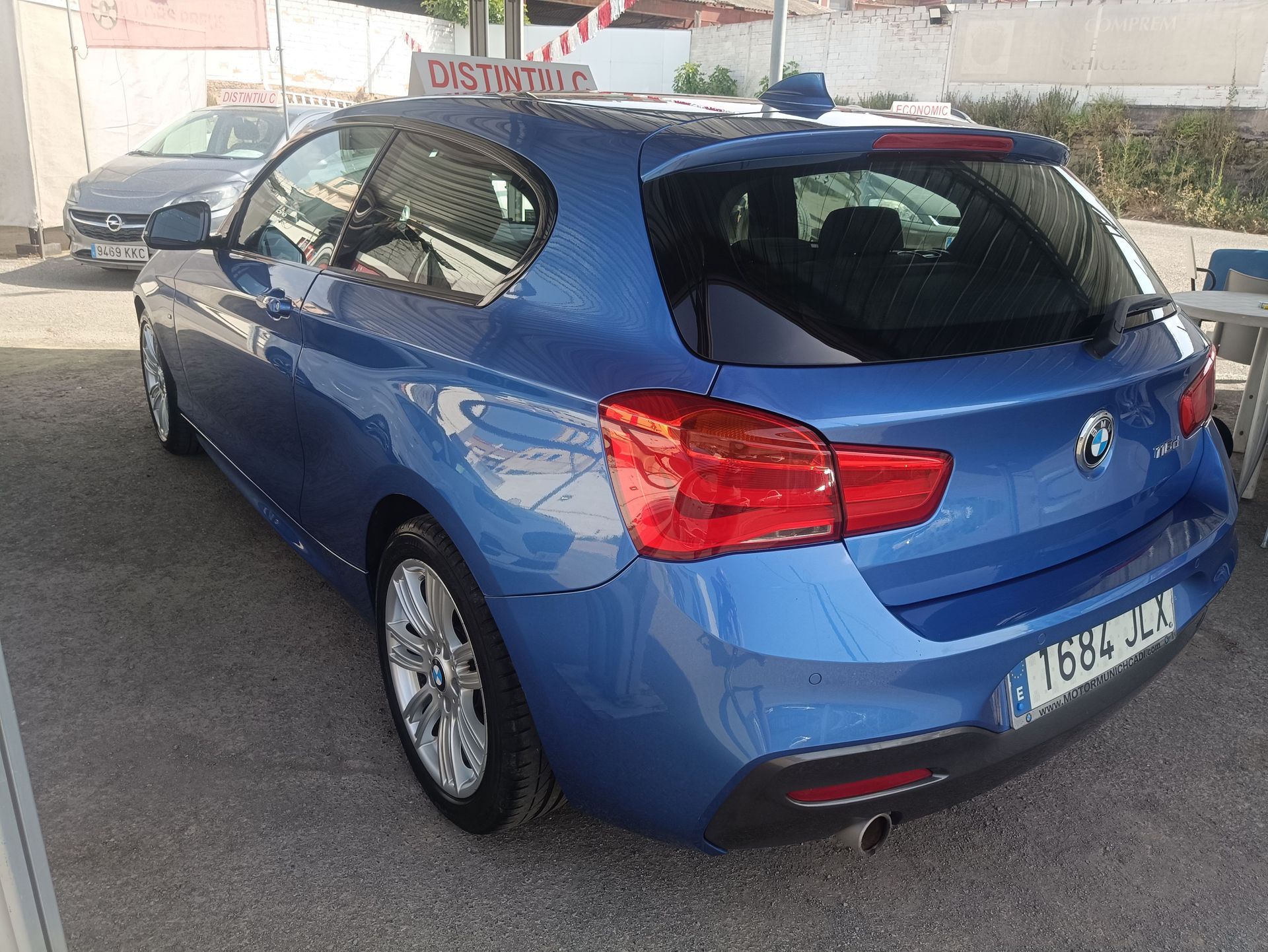 Coche compacto plateado aparcado en un estacionamiento, visto desde el lado delantero izquierdo.