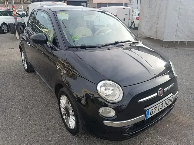 Un Fiat 500 negro está estacionado en un estacionamiento.
