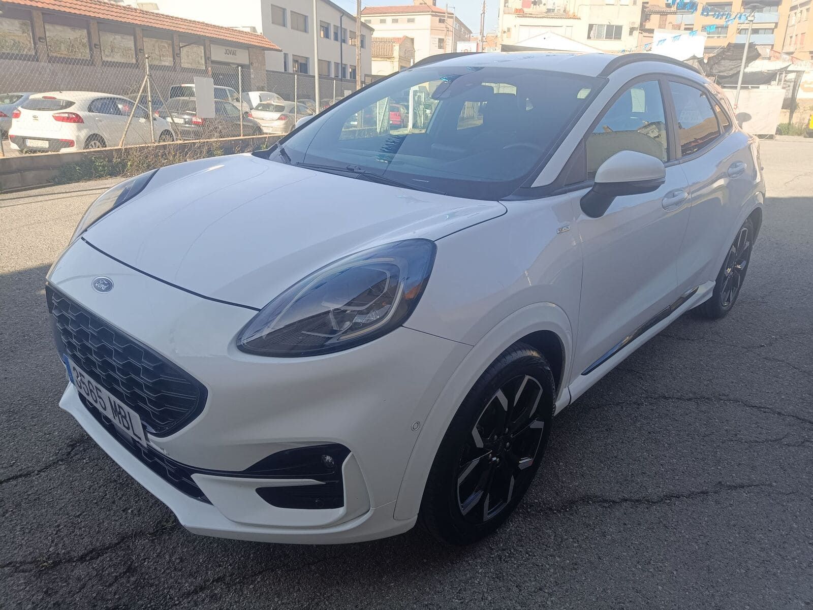 Un Ford Puma crossover blanco estacionado en un aparcamiento de asfalto a plena luz del día.