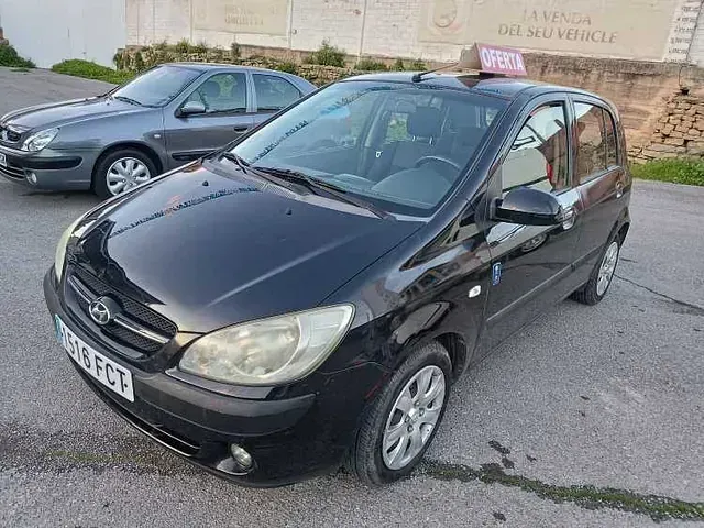 Un coche negro está aparcado junto a un coche gris en un estacionamiento.