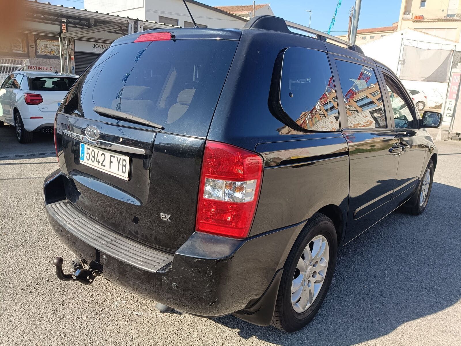 Una furgoneta Kia Carnival negra estacionada al aire libre, vista desde un ángulo de tres cuartos trasero.